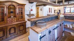 A rustic kitchen with wooden cabinetry, a stone backsplash, and a wooden island with black metal handles. - Vacation home Aualm by Interhome (Forstau)