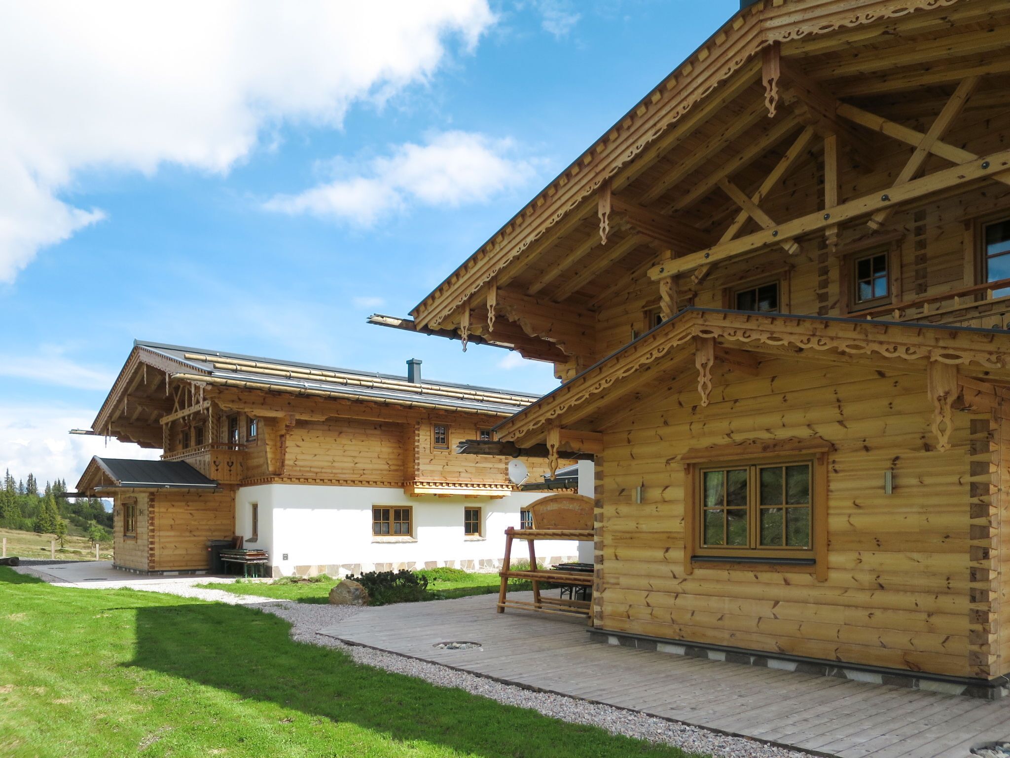 A wooden chalet with a sloped roof, a covered porch, and a stone pathway leading to the entrance.