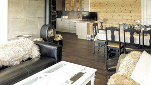 Un salon moderne avec une cheminée, un coin repas avec des chaises en bois et une cuisine équipée d’un téléviseur.