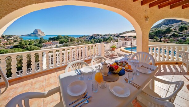 A terrace with a table set for breakfast, overlooking a coastal town and a mountain. - Castillo by Interhome (Calpe/Calp)