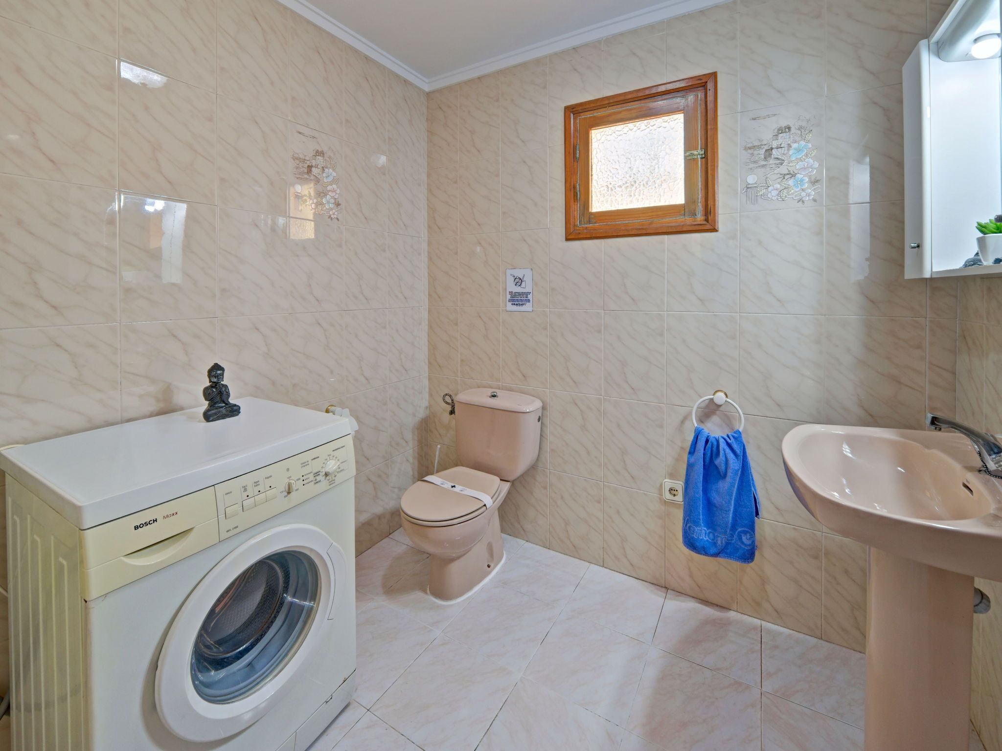 A compact bathroom with a washing machine, toilet, and sink.