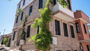 A multi-story building with stone walls and multiple windows. - Cunda Mahmut Bey Konağı (Ayvalik)
