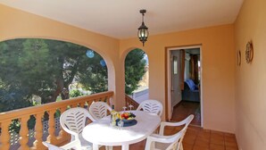 A balcony with a round table and chairs, a hanging light fixture, and a view of trees. - Dulce Vida by Interhome (Calpe/Calp)