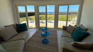 A living room with two sofas, a coffee table, and a view of the sea through large windows.