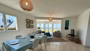 A spacious dining area with a table set for four, a sofa, and a TV stand in the background.