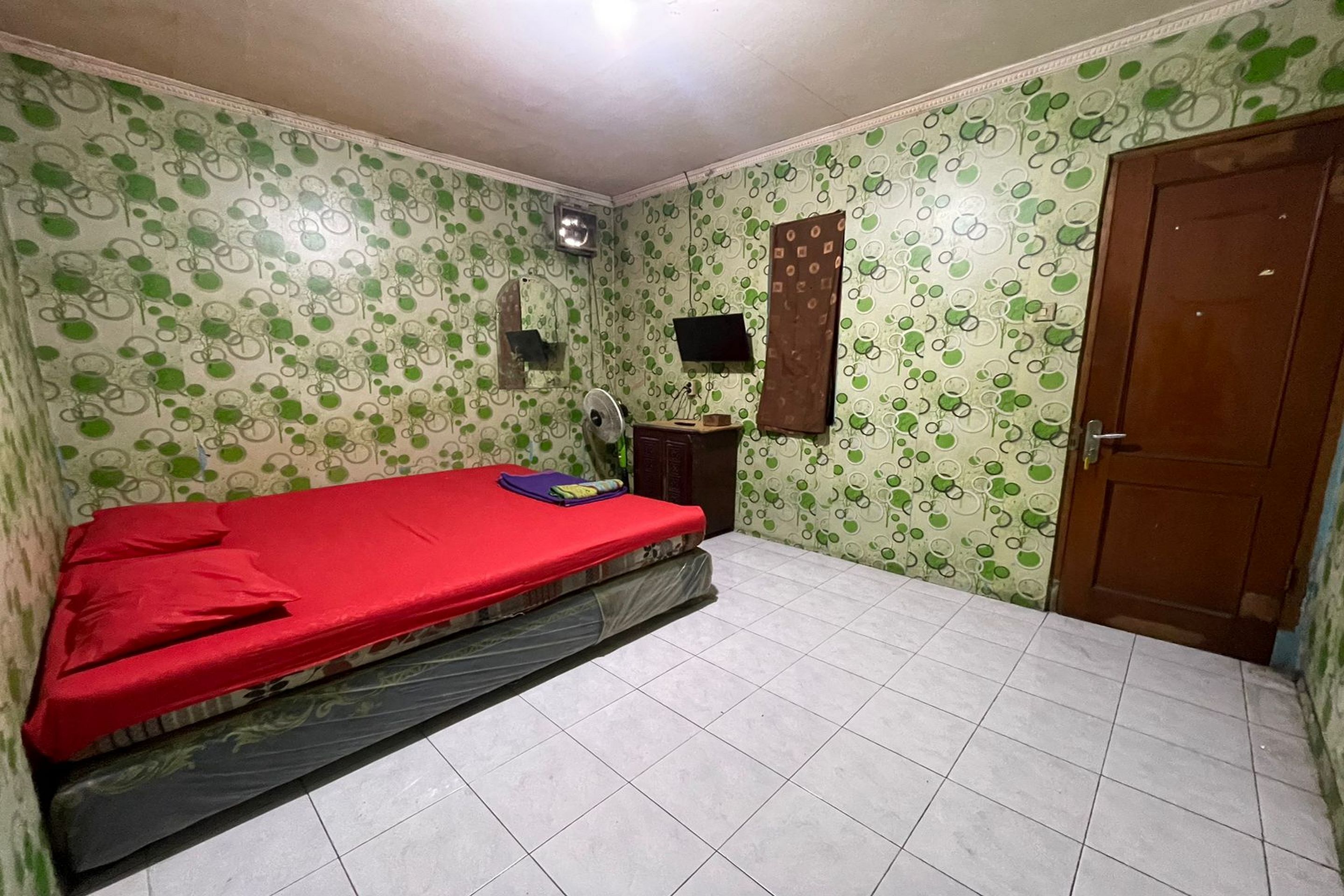 A room with a bed, a TV, and a door.