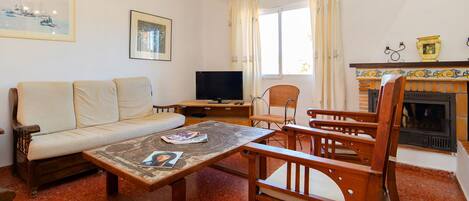 Una sala de estar con sofá, televisión, chimenea y mesa de comedor.