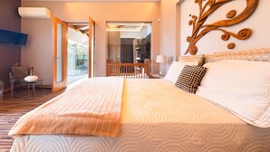 Une chambre d’hôtel moderne dotée d’un grand lit, d’un plafond en bois, d’un téléviseur fixé au mur et d’un balcon avec une porte vitrée.