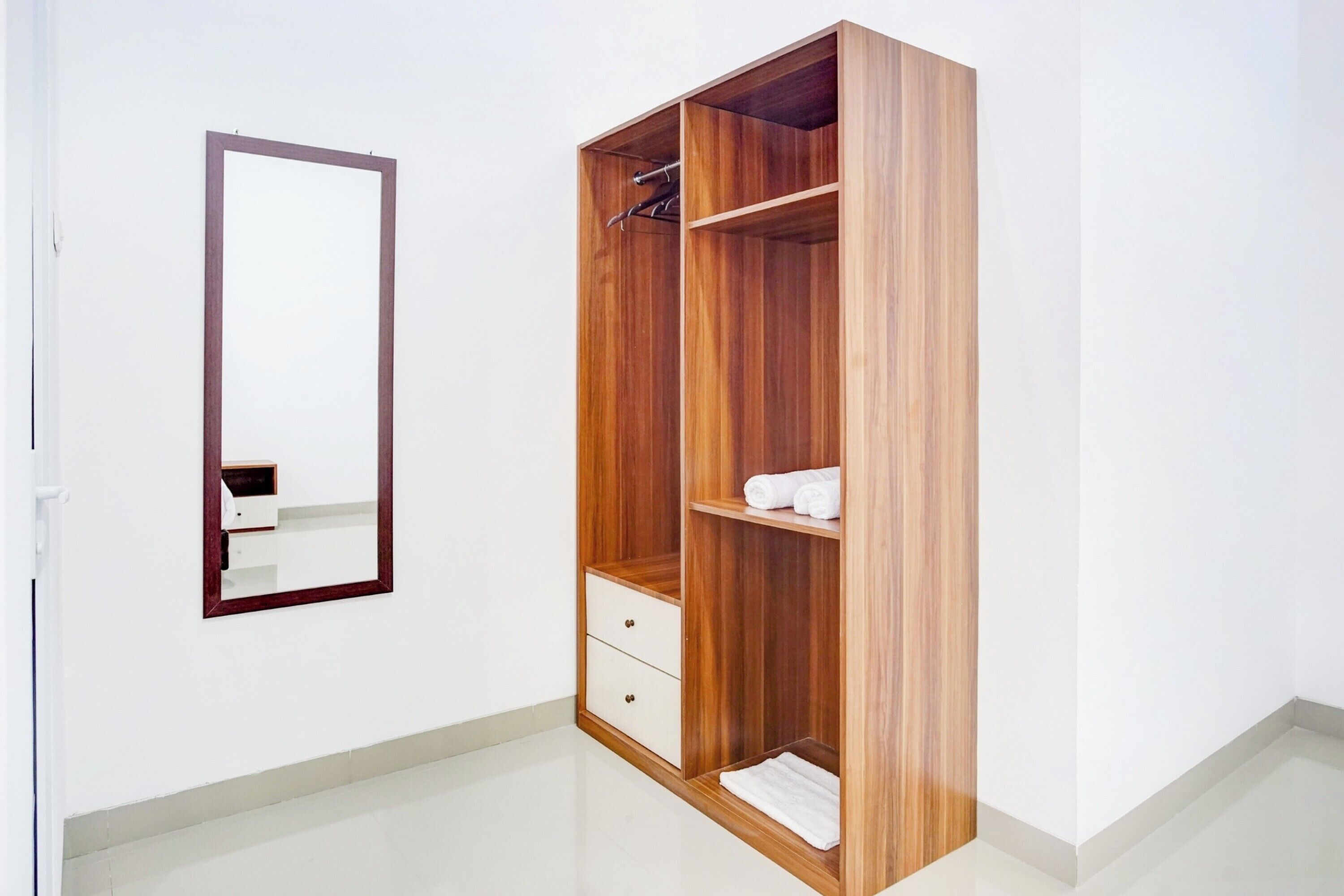 Un armario de madera con un espejo, una repisa con toallas dobladas y un cajón.