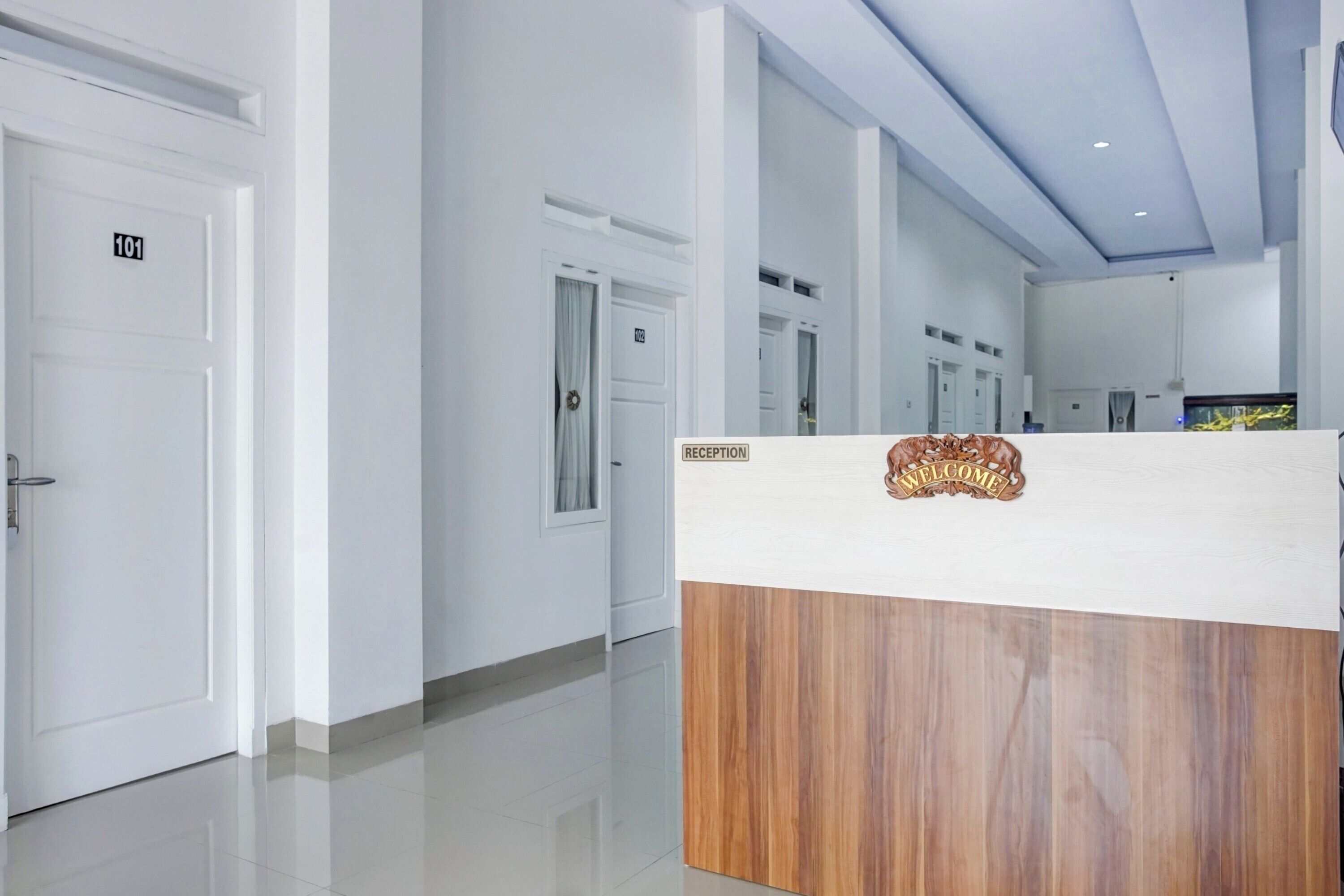A hotel reception area with a reception desk, a reception sign, and a door marked "101".