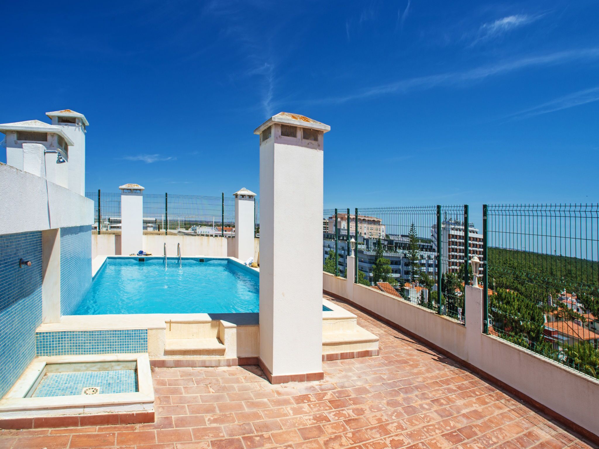 A rooftop swimming pool with a clear view of the cityscape in the background.