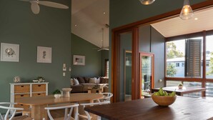 A modern kitchen with a wooden island, white chairs, and a bowl of fruit.