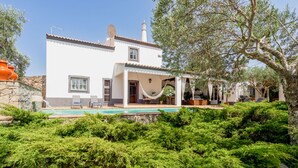 A two-story house with a swimming pool, outdoor seating, and a garden.