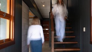 Un couloir avec un escalier en bois, un paillasson sur lequel est inscrit le mot « bonjour », et une fenêtre avec un cadre en bois.