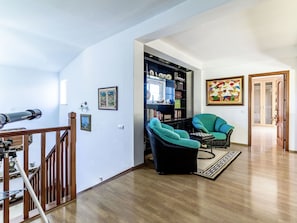 Cozy living area with a high ceiling, wooden staircase, and comfortable seating for relaxation.
