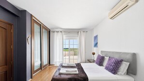 A bedroom with a bed, a nightstand, a window with curtains, and an air conditioning unit. - Monte Meco by Interhome (Silves)
