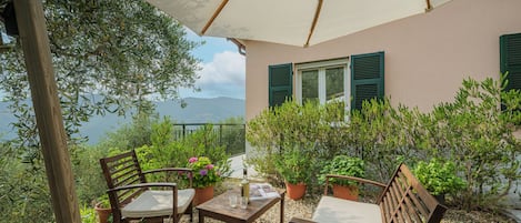 Um terraço com mobiliário de exterior, plantas em vasos e vista para o mar.