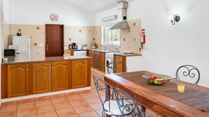 A kitchen with wooden cabinets, a stove, and a dining table with chairs.