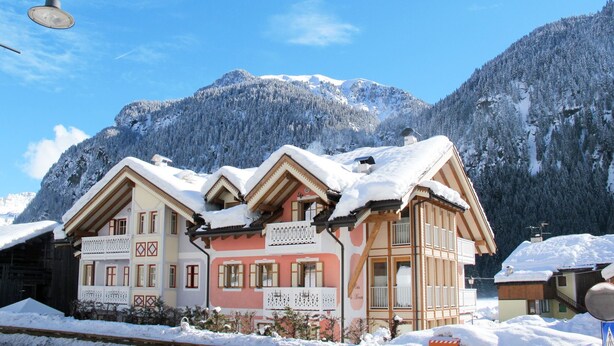 Een hotel in chaletstijl met meerdere balkons en een berg op de achtergrond.