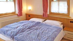 Een slaapkamer met een bed, twee nachtkastjes, een wandlamp en een raam met gordijnen.