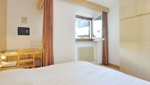 Une chambre à coucher avec un lit, un bureau et une chaise, une fenêtre et un radiateur.
