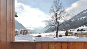 Un balcon en bois offrant une vue sur un paysage enneigé, avec des bâtiments et des montagnes.