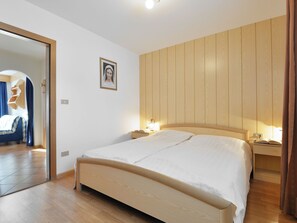 Een moderne slaapkamer met een houten bedframe, een nachtkastje met een lamp en een lijst met een afbeelding aan de muur.