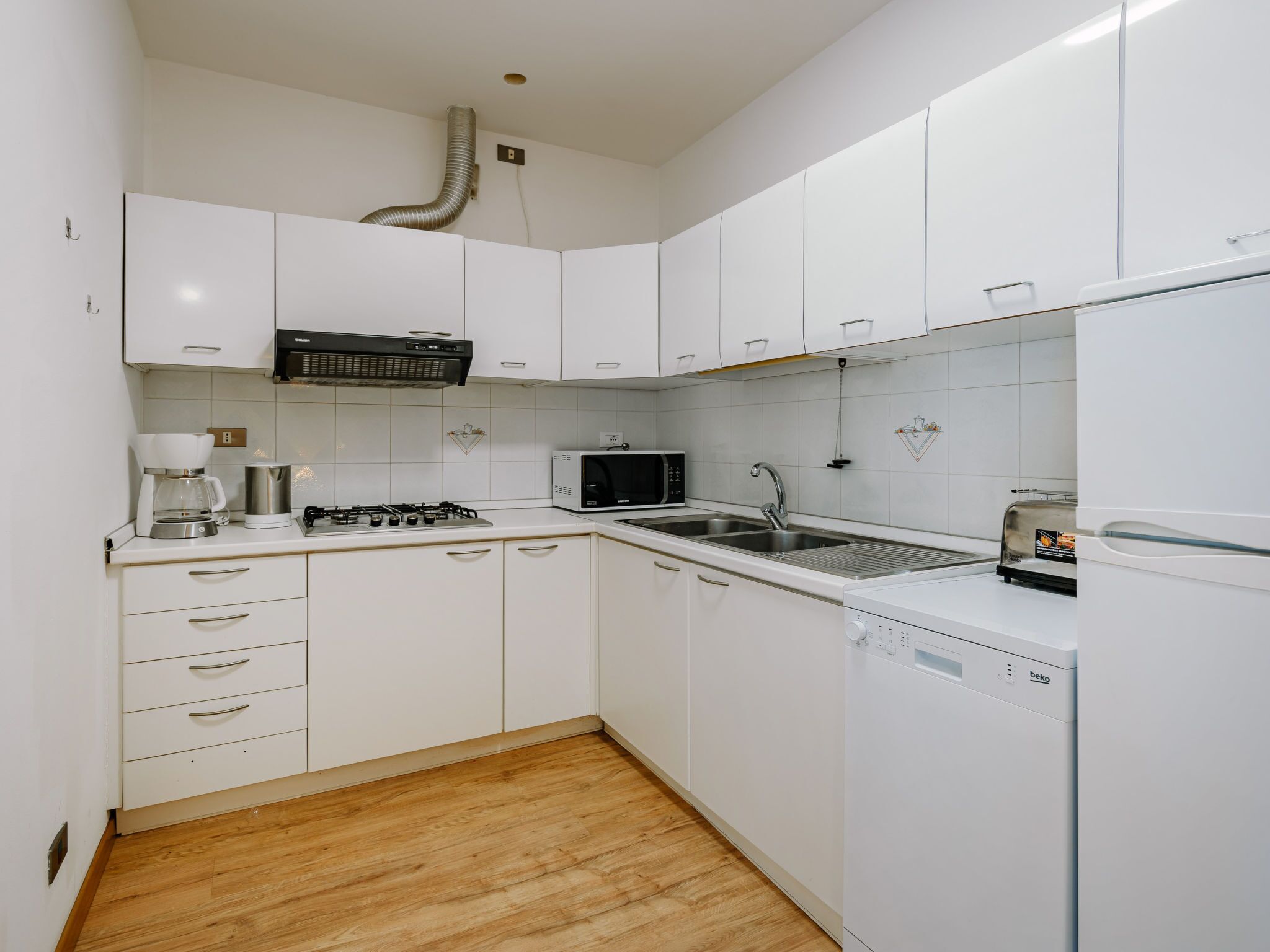 Een koelkast, een magnetron, een vaatwasser, kookgerei, borden en bestek