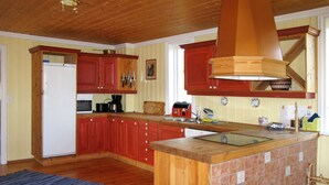 A kitchen with wooden cabinets, a central island, and a tiled backsplash. - Gjefselykkja by Interhome (Skeikampen)