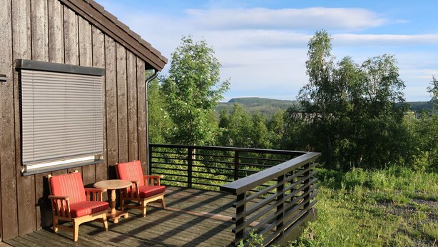 A wooden deck with a railing, a red chair, and a table. - Gjefselykkja by Interhome (Skeikampen)