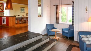 A cozy interior with a wooden ceiling, a kitchen area, and a seating area with blue chairs and a small round table. - Gjefselykkja by Interhome (Skeikampen)