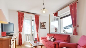 A cozy living room with a red sofa, a wooden coffee table, and a television on a wooden cabinet.