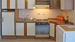 Een functionele keuken met een koelkast, fornuis, spoelbak en vaatwasser.