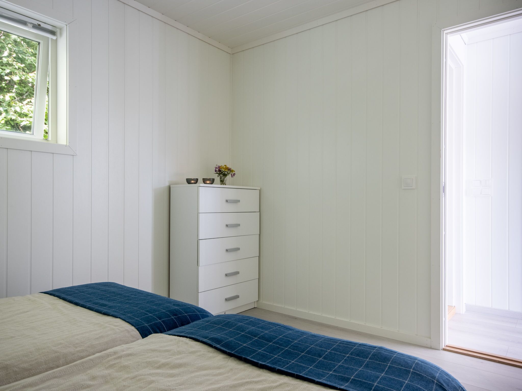 Een slaapkamer met een bed, een kapstok en een raam.