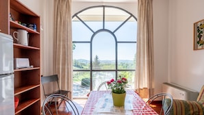 Un coin repas avec une table dressée pour deux personnes, une bibliothèque et une vue dégagée sur l’extérieur grâce à une grande fenêtre en arc de cercle.
