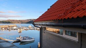 A view of a marina with boats docked, a wooden building with a red roof, and a clear sky. - Jektastøo by Interhome (Huglo)