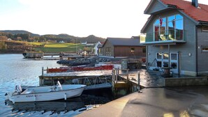 A waterfront property with a dock, a boat, and a house with a balcony overlooking the water. - Jektastøo by Interhome (Huglo)