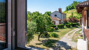 A view from a window overlooking a rural landscape with a building that has a tiled roof and a bell tower. - Cascina Villa (AST231) by Interhome (Asti)
