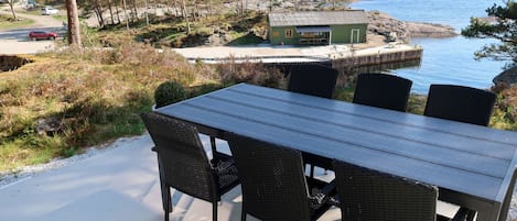 A dining area with a table and chairs, overlooking a lake and mountains.