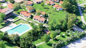 An aerial view of a residential area with houses, a swimming pool, and a beach.