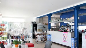 Un café moderno con una barra, una estantería llena de objetos varios y una mesa con sillas.