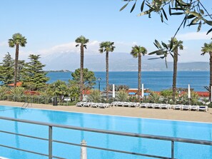 Vista a la piscina con una panorámica despejada del mar y montañas al fondo.