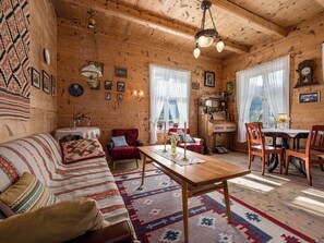 A cozy wooden cabin with a sofa, dining table, and chairs.