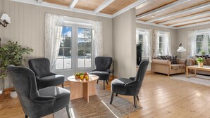 A spacious living room with wooden floors, a large window, and a cozy seating area. - Vacation home Haven by Interhome (Birkeland)