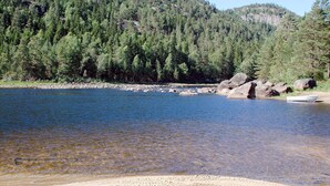 A clear lake surrounded by dense forest and rocky terrain. - Vacation home Haven by Interhome (Birkeland)