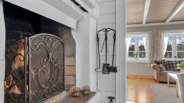 A cozy living room with a fireplace, a sofa, and a window with curtains. - Vacation home Haven by Interhome (Birkeland)