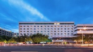 Et moderne hotel med flere etager, mange vinduer og et godt oplyst indgangsparti.