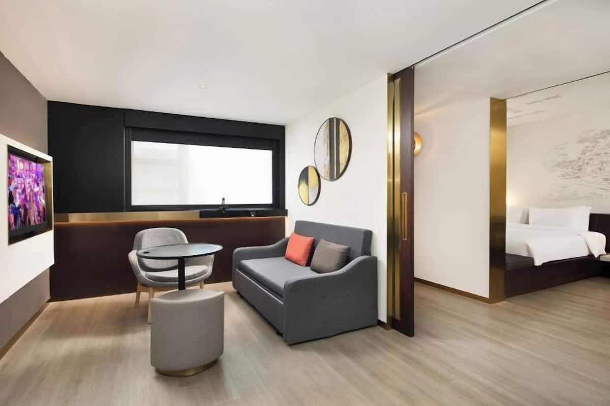 A modern hotel room with a sofa, ottoman, and a small table.