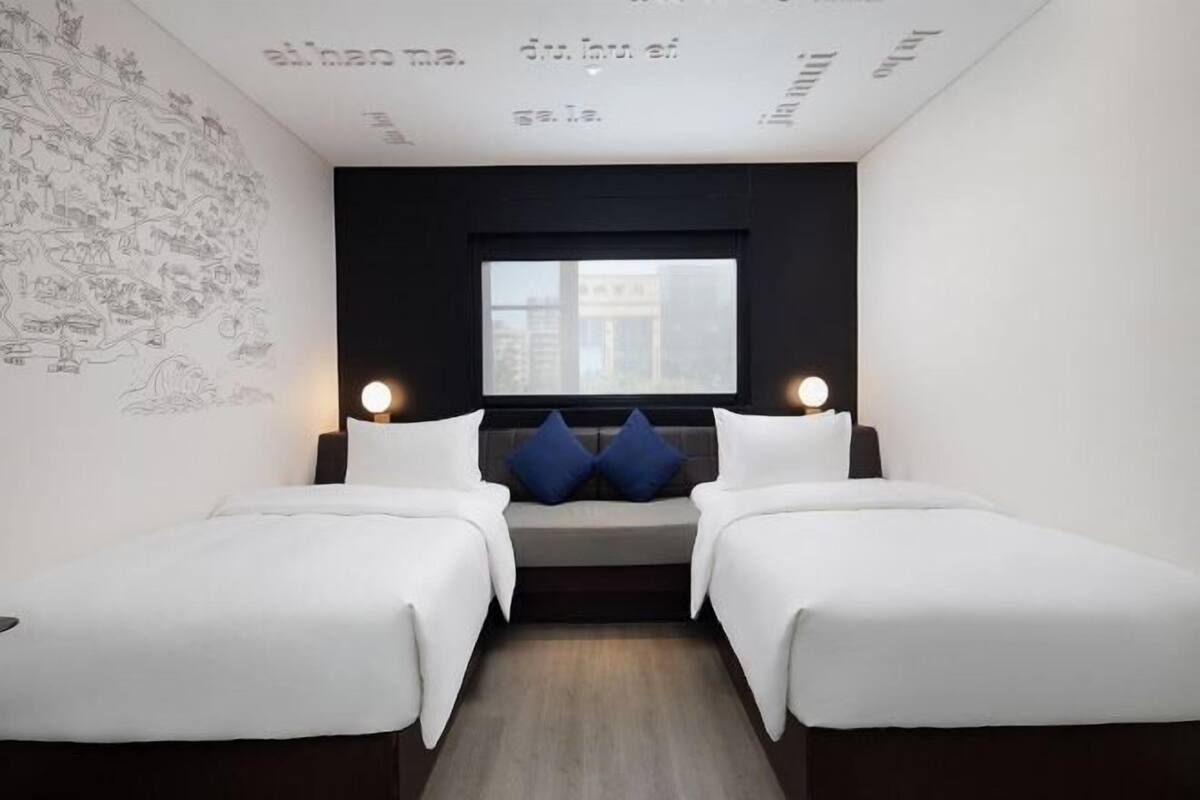 A hotel room with two beds, a large window, and a wall with a map.