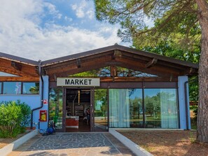 A building with a sign reading 'MARKET' at the entrance, a covered outdoor area, and a stone-paved entrance. - The Garda Village by Interhome (Sirmione)